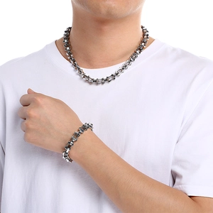 Detail of silver stainless steel bamboo chain necklace and bracelet on model wearing white tee
