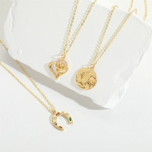 Three elegant gold necklaces featuring rose heart, embossed coin, and gem horseshoe pendants
