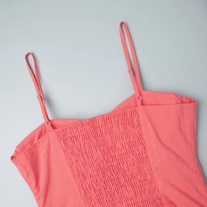 Detail of coral cotton dress with adjustable straps and elastic gathered back design