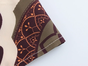 Detailed macro view of woven fabric featuring ethnic prints and white seam stitching