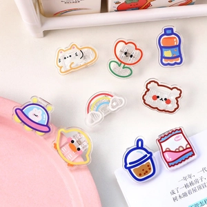 Set of 9 cute cartoon acrylic clips for snack sealing and paper organizing on a desk
