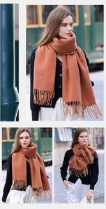 Detailed view of caramel cashmere-like scarf with fringe tassels on European street background