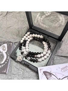 Detail of black and white natural stone beaded bracelets with silver heart charms