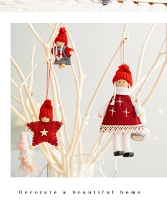 Detail of felt Christmas ornaments including red angel doll and star on white branches