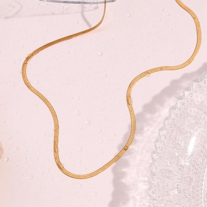 Detailed flat lay of a 2mm gold-plated stainless steel snake chain on a water-beaded surface