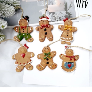Detail van zes peperkoekman kersthangers met touwtjes op een achtergrond van dennentakken