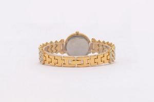 Detail view of gold metal watch with diamond accents and chain bracelet folding clasp