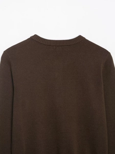 Detail of the dark brown knitted sweater showing the ribbed neckline and shoulder texture