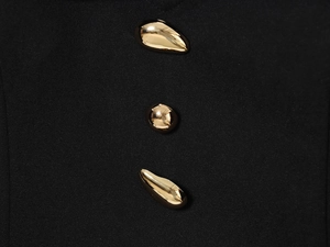 Detail of three golden irregular metal buttons on premium black ribbed fabric texture