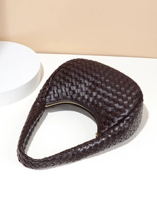 Dark brown woven leather crescent shoulder bag with golden zipper on a minimalist background