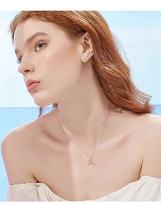 Rose gold jewelry set with fishtail necklace and pearl earrings on a model