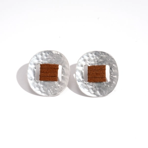 Modern silver earrings with hammered texture and brown leather wrap details on white background