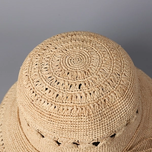 Gros plan du sommet du chapeau de paille tissé main avec texture ajourée et finition beige
