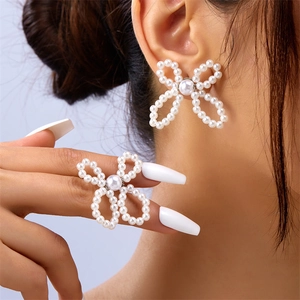 Close-up of a woman wearing oversized white faux pearl bow earrings in a stylish shot