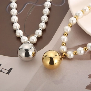 Detailed view of pearl necklaces with large gold and silver metallic orb pendants