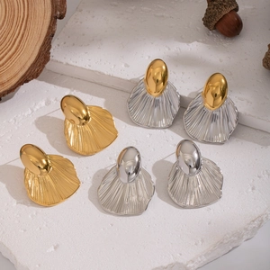 Minimalist geometric leaf-shaped earrings in gold and silver finish on stone background