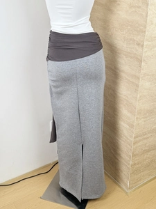 Detail view of the gray knitted maxi skirt featuring a dark gray pleated patchwork waistband