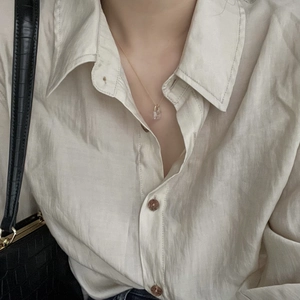Close-up of a minimalist gold necklace with a clear square lock pendant on a model
