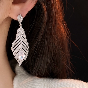 Gros plan de boucles d'oreilles feuilles à pampilles serties de zircons sur l'oreille
