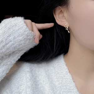 Close-up of golden irregular liquid metal style earrings with minimalist flowing design