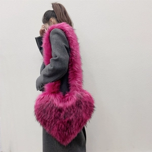 Faux raccoon fur heart-shaped crossbody bag in magenta plush on a grey wool coat