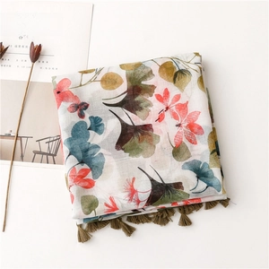 Détail d'une écharpe bohème avec motifs floraux rouges et pompons vert olive
