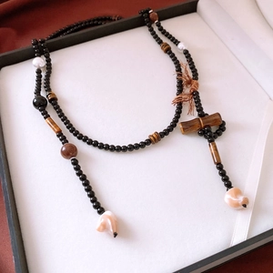 Macro shot of ethnic necklace with tiger eye beads, pearls and brown tassels in gift box
