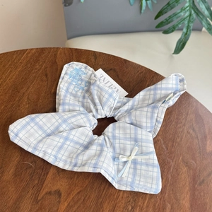 Close-up of light blue checkered scrunchie with floral embroidery and white ribbon bow