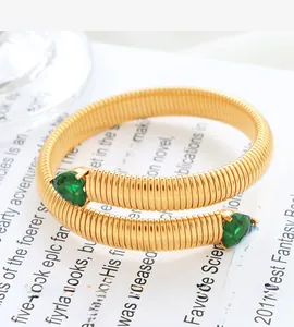 Detailed macro view of golden spiral snake bone bracelet with heart shaped green gems