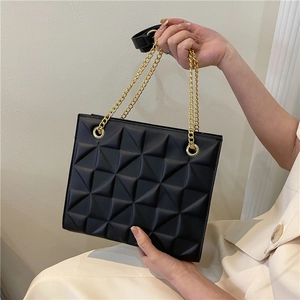 Detail of matte black bag with geometric triangle embossing and gold chain straps