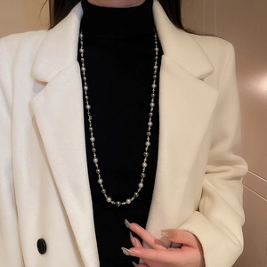 Détail d'un collier de perles gris argenté avec breloques lune et étoile sur mannequin