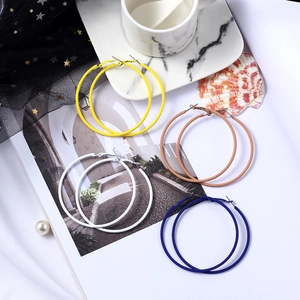 Mise à plat de boucles d'oreilles créoles mates en jaune beige blanc et bleu sur magazine