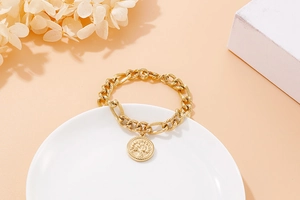 Detail of gold curb chain bracelet with embossed Tree of Life coin pendant