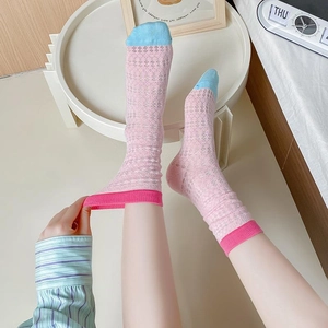 Pink mesh crew socks with red rib cuffs and blue toes shown on model in bedroom