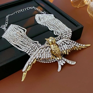 Macro shot of layered necklace showing gold swallow pendant with sparkling rhinestones