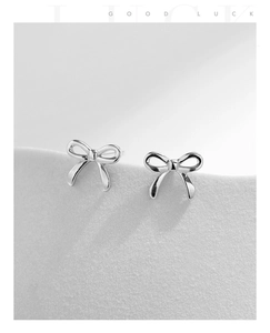 Detailed view of elegant silver bow earrings featuring polished metallic luster on a light gray surface