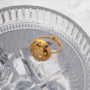 Detailed close-up of a hollow gold dome ring with heart patterns set in ice and glass