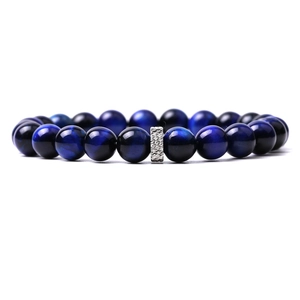 Macro detail of blue tiger eye beads and an intricate silver metal charm on the bracelet
