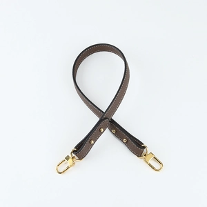 Close-up of litchi pattern leather shoulder strap with gold lobster clasps and stitching