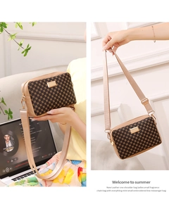 Detail of a beige and brown crossbody bag featuring geometric patterns and a metal plate