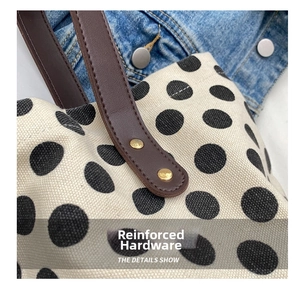 Detail of leather handles with gold rivet reinforcement on polka dot canvas tote bag