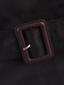 Detailed macro view of the adjustable belt buckle on a short women's trench coat jacket