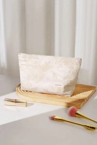 Gros plan sur la trousse à maquillage en coton et lin blanc avec broderie florale