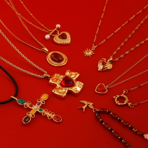 Flat lay of vintage gold stainless steel necklaces with red agate and baroque pendants