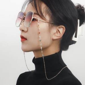 Golden eyewear chain with colorful enamel hearts on a model against white background