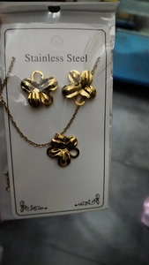 Detailed macro view of gold four-leaf clover necklace and earrings on steel display card