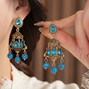 Detail of vintage chandelier earrings with blue rhinestones and turquoise beads in gold finish