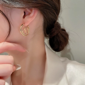 Close-up of elegant gold CD letter heart earrings shown on a model for an upscale style