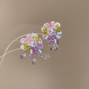 Macro shot of handmade beaded flower earrings with pink petals and purple drop crystals