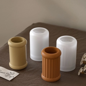 Macro detail of ribbed and smooth textured cylindrical candle holders in earthy tones